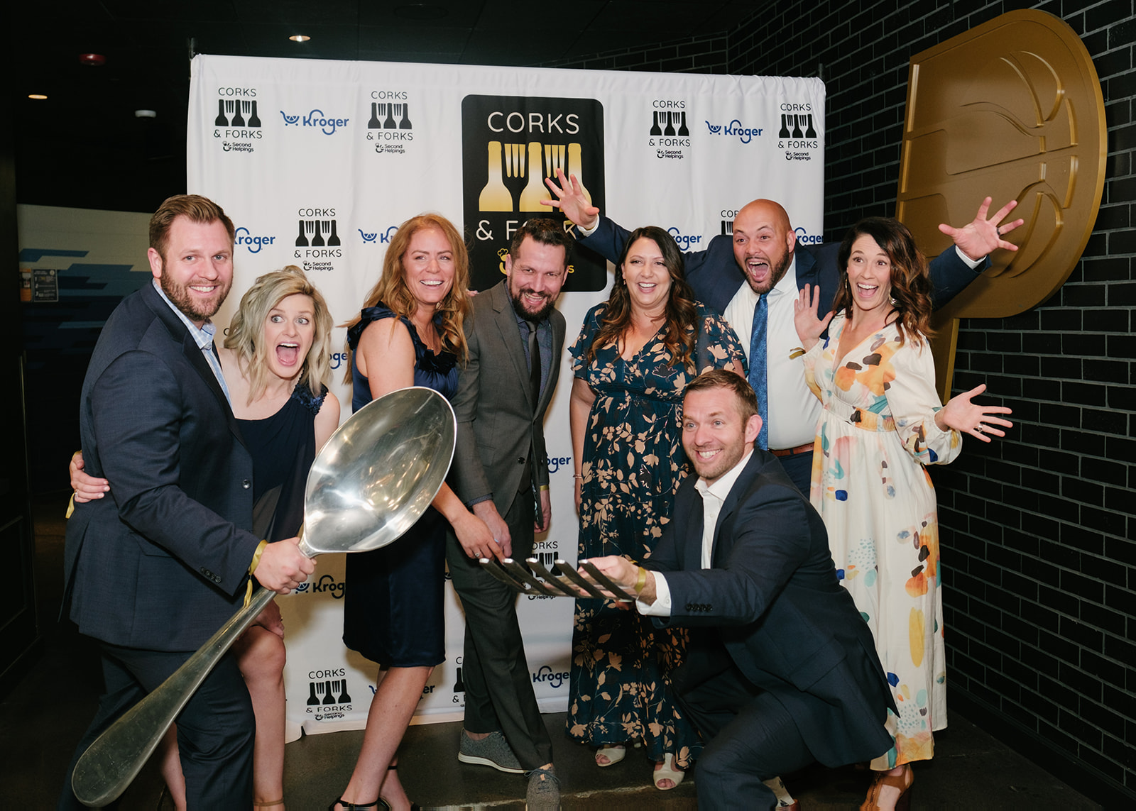 Group of people posing in from of a Corks & Forks backdrop